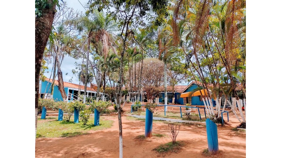 Área externa frente às instalações da clínica de recuperação, sob a sombra de lindas árvores
